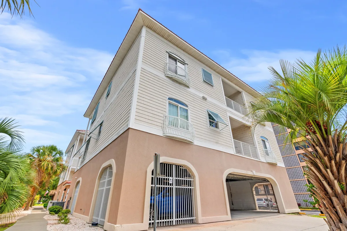 The exterior of the building with prominent balconies, tall palm trees, and inviting architectural details, suggesting both comfort and resort luxury. The scene hints at leisurely balcony moments and strolls through lush communal areas.